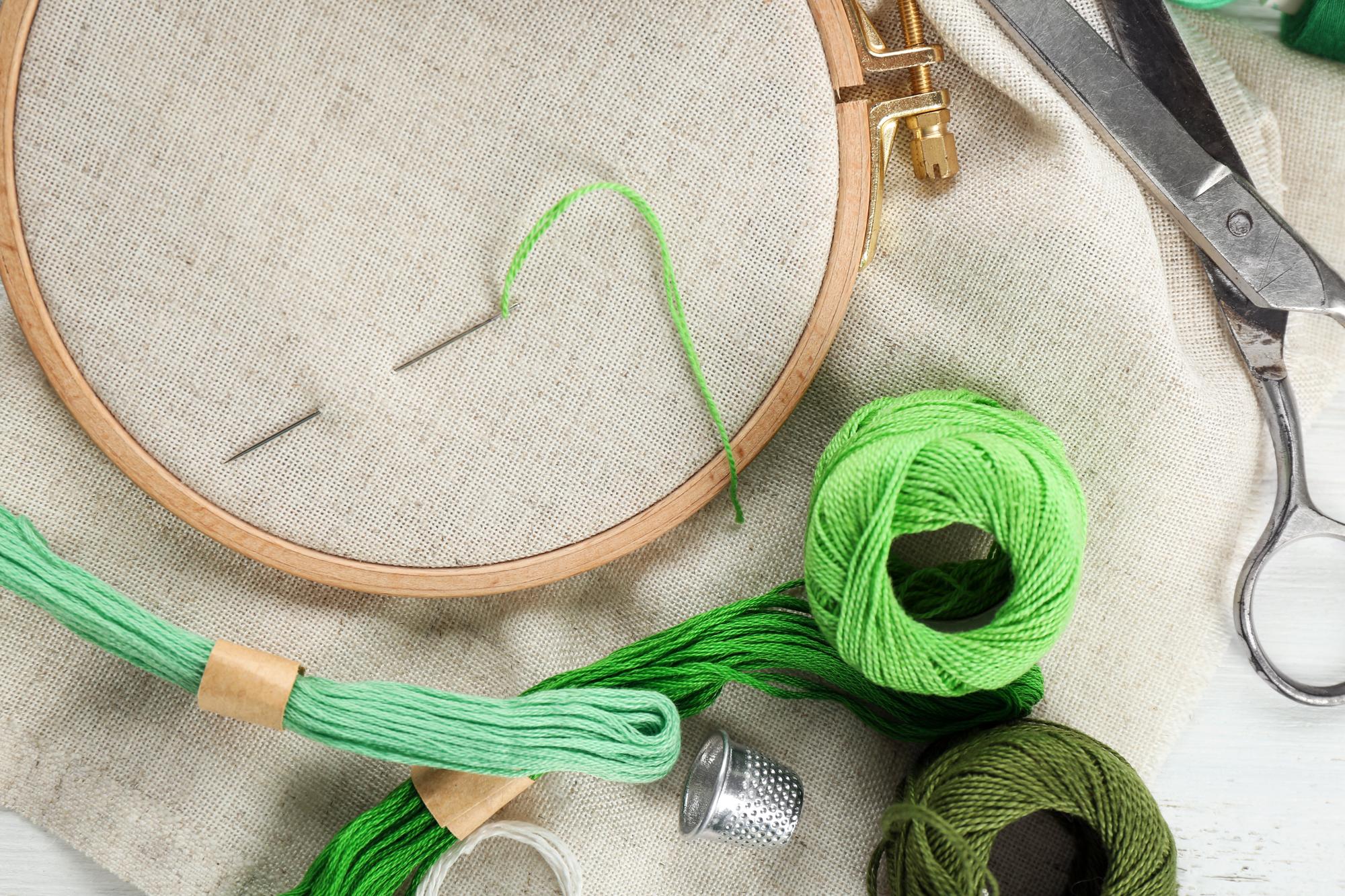 Close-up of hand-guided embroidery frame with threads